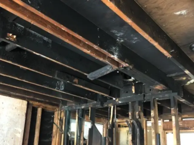 Fire-charred ceiling joists and framing stripped back to the structure