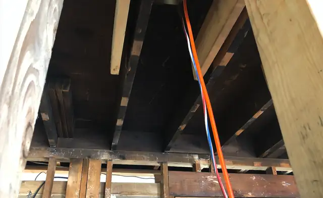Burned joists overhead with an orange cord hanging down