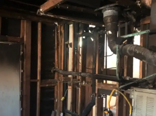 Burned studs and plumbing near a water heater after a fire