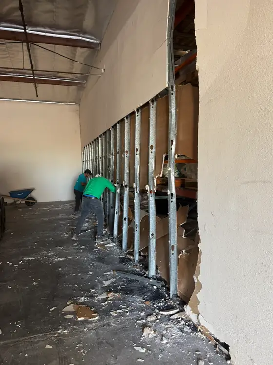 Crew taking down a metal stud wall in a warehouse space