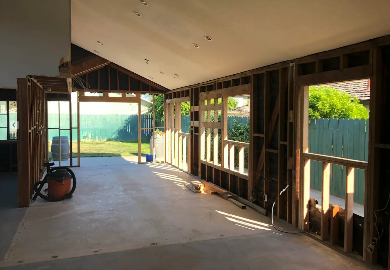 Inside a house gutted to the wall studs, with sunlight coming through the open framing