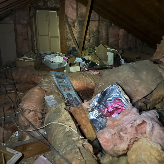 Cluttered attic with old, matted fiberglass insulation and torn duct wrap