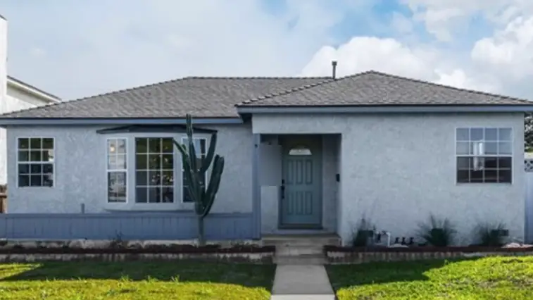 Same house with a new dark shingle roof and a teal front door