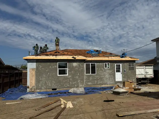 Crew tearing off the old roof on a stucco house