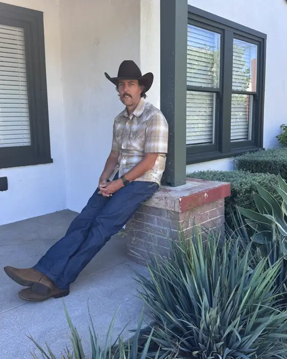 Shawn, owner of Lighthouse Cleanup and Demolition Services, sitting on a brick ledge in a cowboy hat